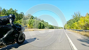 Aerial shot of man riding fast on modern sport motorbike at highway during summer day. Motorcyclist racing his