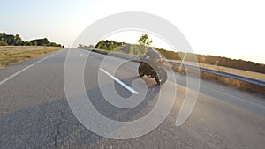 Aerial shot of man riding fast on modern sport motorbike at highway during sunset. Motorcyclist racing his motorcycle on