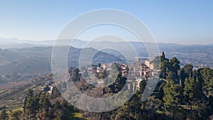 Aerial shot of the medieval village of Montemaggiore al Metauro with a church and trees around