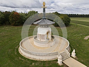 Aerial shot of the Milton Keynes Peace Pagoda in England surrounded by a green field