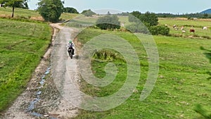 aerial shot of a motocross rider on a journey on a dirt and dusty country road driving fast and exploring beautiful