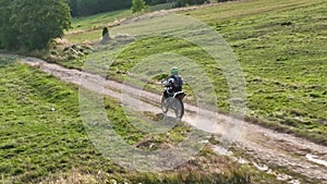 aerial shot of a motocross rider on a journey on a dirt and dusty country road driving fast and exploring beautiful