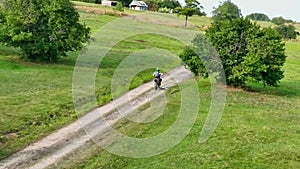 aerial shot of a motocross rider on a journey on a dirt and dusty country road driving fast and exploring beautiful