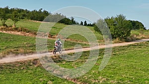 aerial shot of a motocross rider on a journey on a dirt and dusty country road driving fast and exploring beautiful