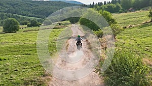 aerial shot of a motocross rider on a journey on a dirt and dusty country road driving fast and exploring beautiful