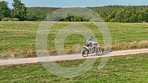 aerial shot of a motocross rider on a journey on a dirt and dusty country road driving fast and exploring beautiful