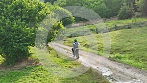 aerial shot of a motocross rider on a journey on a dirt and dusty country road driving fast and exploring beautiful
