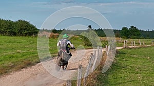 aerial shot of a motocross rider on a journey on a dirt and dusty country road driving fast and exploring beautiful