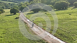 aerial shot of a motocross rider on a journey on a dirt and dusty country road driving fast and exploring beautiful