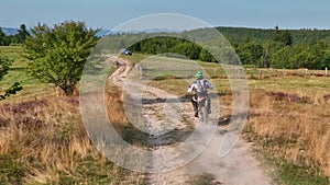 aerial shot of a motocross rider on a journey on a dirt and dusty country road driving fast and exploring beautiful