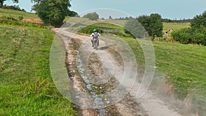 aerial shot of a motocross rider on a journey on a dirt and dusty country road driving fast and exploring beautiful