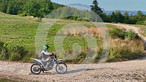 aerial shot of a motocross rider on a journey on a dirt and dusty country road driving fast and exploring beautiful