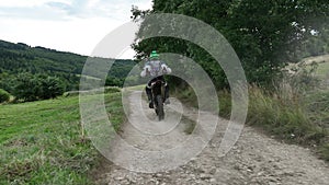 aerial shot of a motocross rider on a journey on a dirt and dusty country road driving fast and exploring beautiful