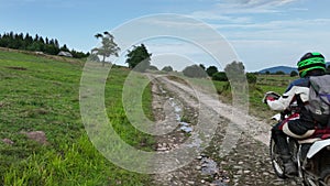 aerial shot of a motocross rider on a journey on a dirt and dusty country road driving fast and exploring beautiful