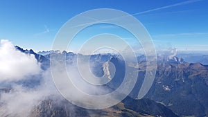 Aerial shot of a mountain range summit covered with clouds on a sunny day