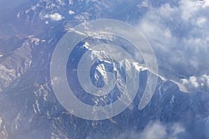 Aerial shot of mountain ranges with thin clouds covering some parts of it