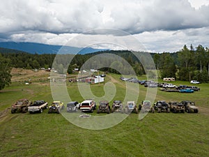 Aerial shot of off-road vehicles in a grass field near trees