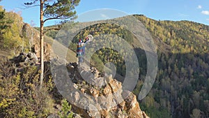 Aerial shot of an old wizard in a bright shaman costume dancing with a tambourine on a mountain top.