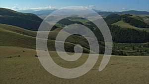 Aerial shot of open rangeland with forest and mountains