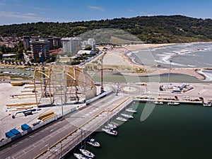 Aerial shot over a beautiful port with many boats and ships, buildings and green mountain