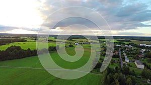 Aerial shot over lush green fields and meadows. Sunset.