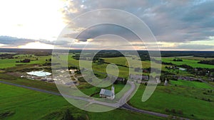 Aerial shot over lush green fields and meadows. Sunset.