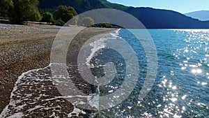 Aerial shot of pebbly beach and sea in Greece from drone taking off near-horizontally