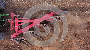 Aerial shot of a Plow processing a dry Soil field.