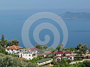 Aerial shot of pure water houses and green-covered hills of the George House, Faralya, Turkey