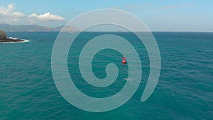 Aerial shot of a red buoy in a beautiful blue sea