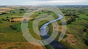 Aerial shot of a river surrounded by green field in summer, Tykocin, Poland