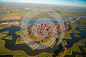 Aerial shot of a river surrounded by plowed fields separated by patterned lines, Heusden