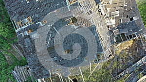 Aerial shot of a ruined rooftop of a soviet cattle barn. Camera moving backwards