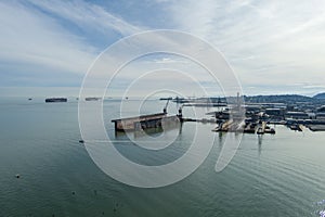 aerial shot of the San Francisco Bay with cargo ships on the rippling ocean water, cranes, buildings, blue sky and clouds