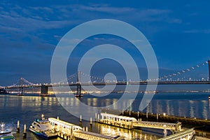 aerial shot of the San Francisco Oakland Bay Bridge with lights at night with ships sailing in the bay San Francisco California