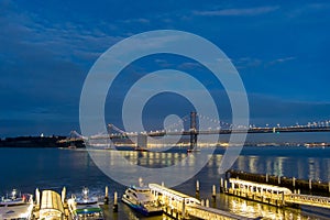 aerial shot of the San Francisco Oakland Bay Bridge with lights at night with ships sailing in the bay San Francisco California