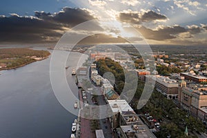 aerial shot of the Savannah River with ships docked along the banks and sailing on the water with restaurants, shops