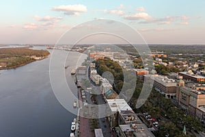 aerial shot of the Savannah River with ships docked along the banks and sailing on the water with restaurants, shops