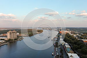 aerial shot of the Savannah River with ships docked along the banks and sailing on the water with restaurants, shops