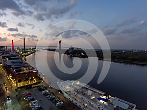 aerial shot of the Savannah River at sunset with the Talmadge Memorial Bridge, ships docked along the banks with restaurants