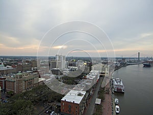 aerial shot of the Savannah River at sunset with the Talmadge Memorial Bridge, ships docked along the banks with restaurants