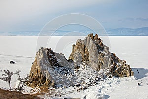 Aerial shot of Shamanka rock on Olkhon island in winter. Frozen lake Baikal in daylight, Siberia, Russia. Drone flies above