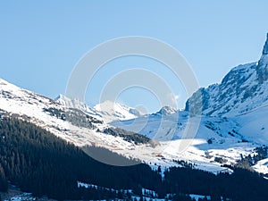 An aerial shot shows Verbier, Switzerland's snowy landscape, ski tracks, a peak