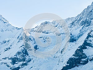 An aerial shot shows Verbier, Switzerland's snowy landscape, ski tracks, a peak