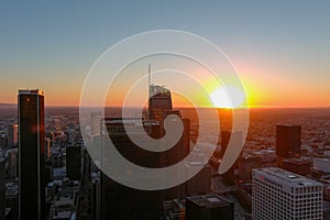 An aerial shot of the skyscrapers and office building in the city skyline with cars driving on the street at sunset in downtown