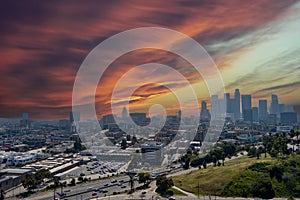 aerial shot of skyscrapers, office buildings and hotels in the city skyline with cars driving on the freeway, lush green trees