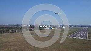 Aerial shot of a small propeller airplane taking off from city airport runway on a sunny day