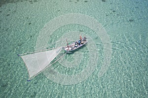 Aerial shot of small shrimp fishing boat in clear water in Thailand