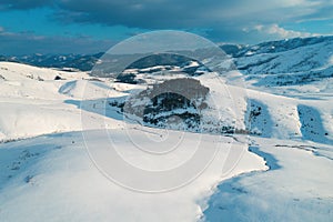 Aerial shot of snow-capped hill top lit by the setting sun in winter sunset at Zlatibor