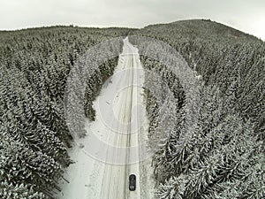 Aerial shot of snow-covered road in the countryside Carpathian Mountains with car on way